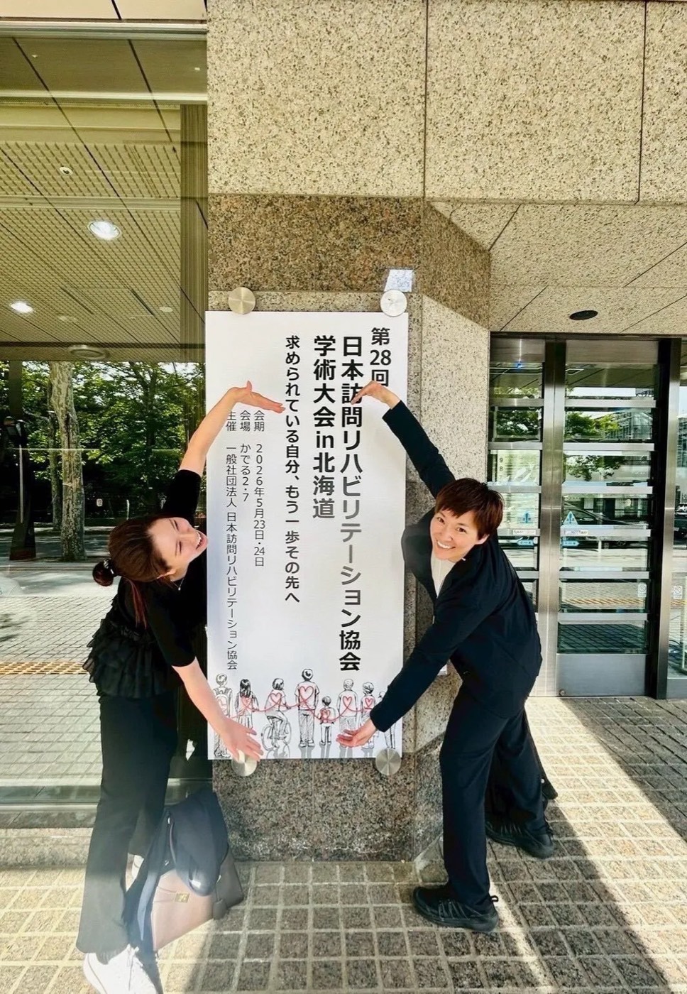 学会会場の前に立つスタッフ